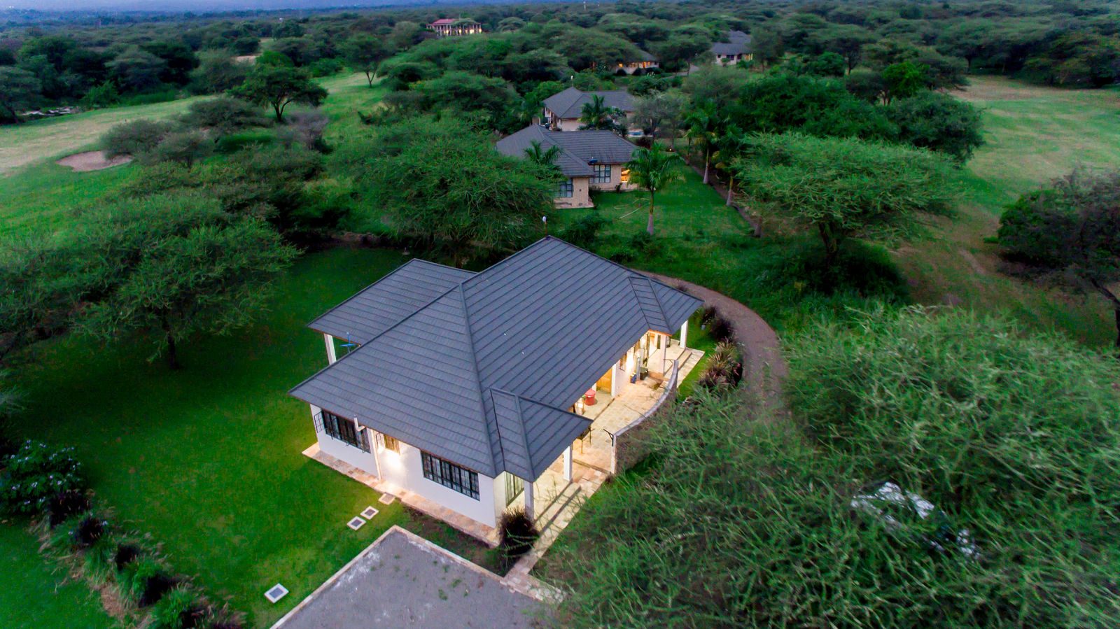 The cottage lit up at dusk, seen from above among the trees