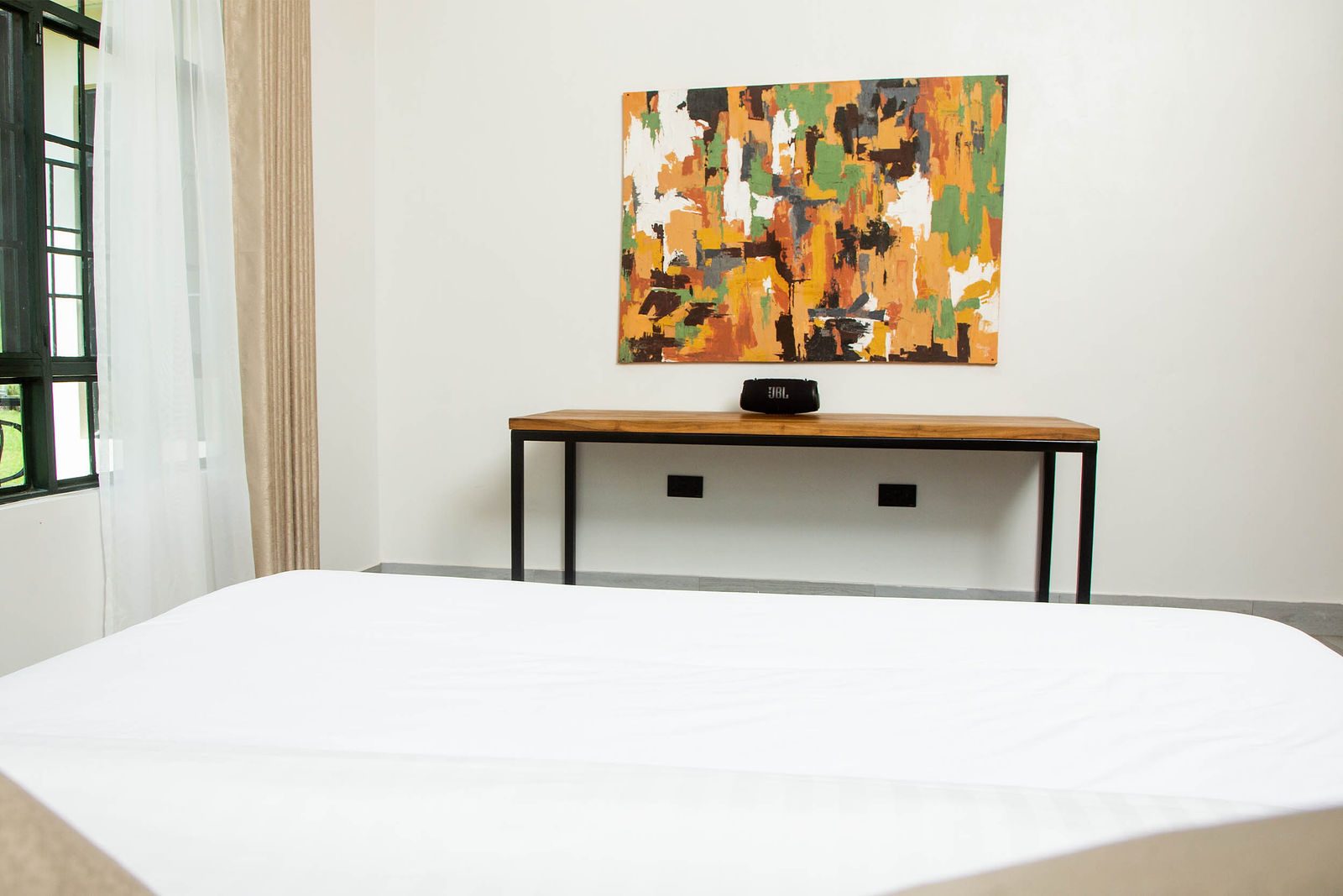 Bedroom with a large bed and a Tanzanian painting above the desk
