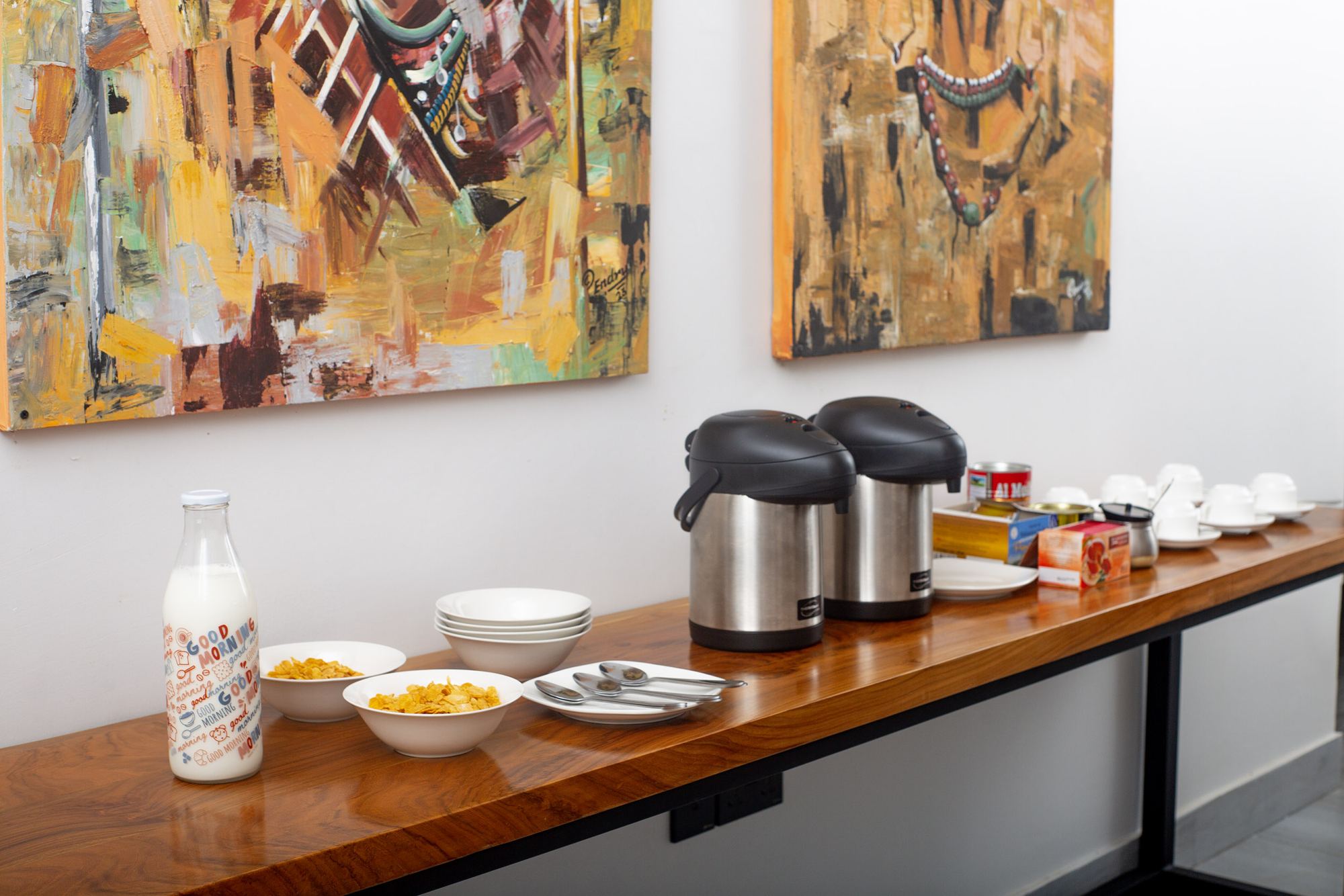 Breakfast set-up with flasks, cereal and fruit under Tanzanian paintings