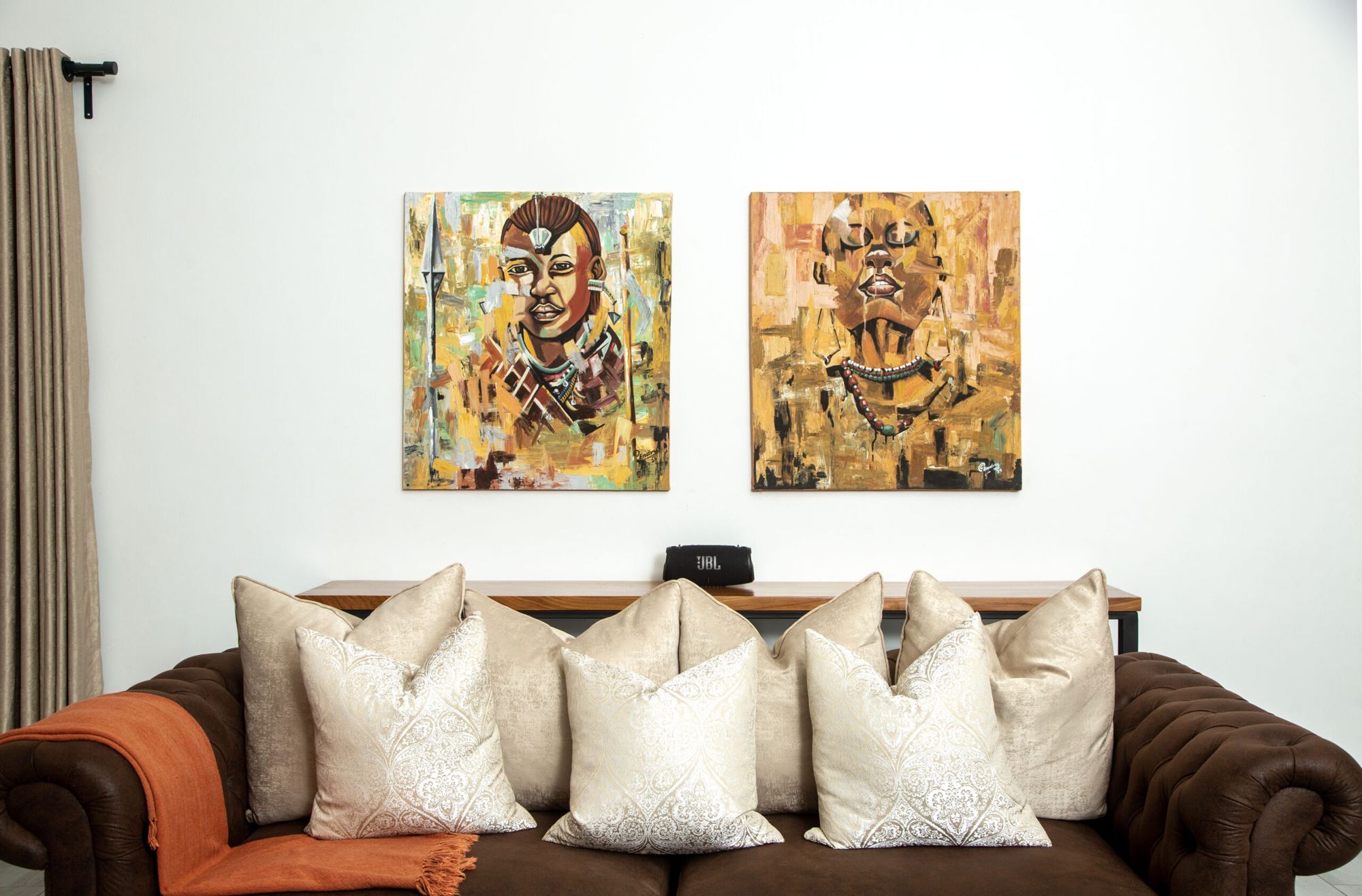 Sofa with cushions under two paintings by Tanzanian artists